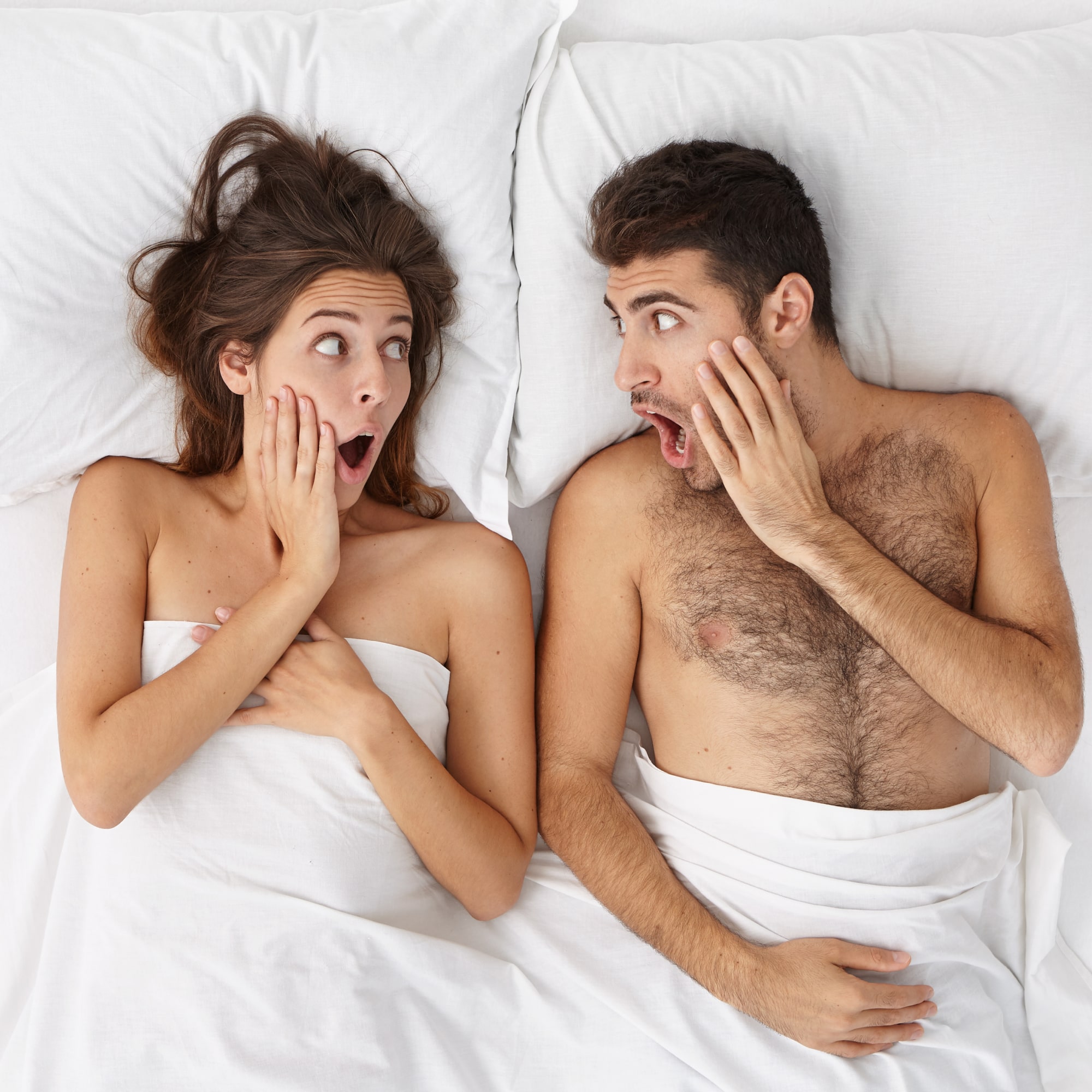couple in bed looking shocked